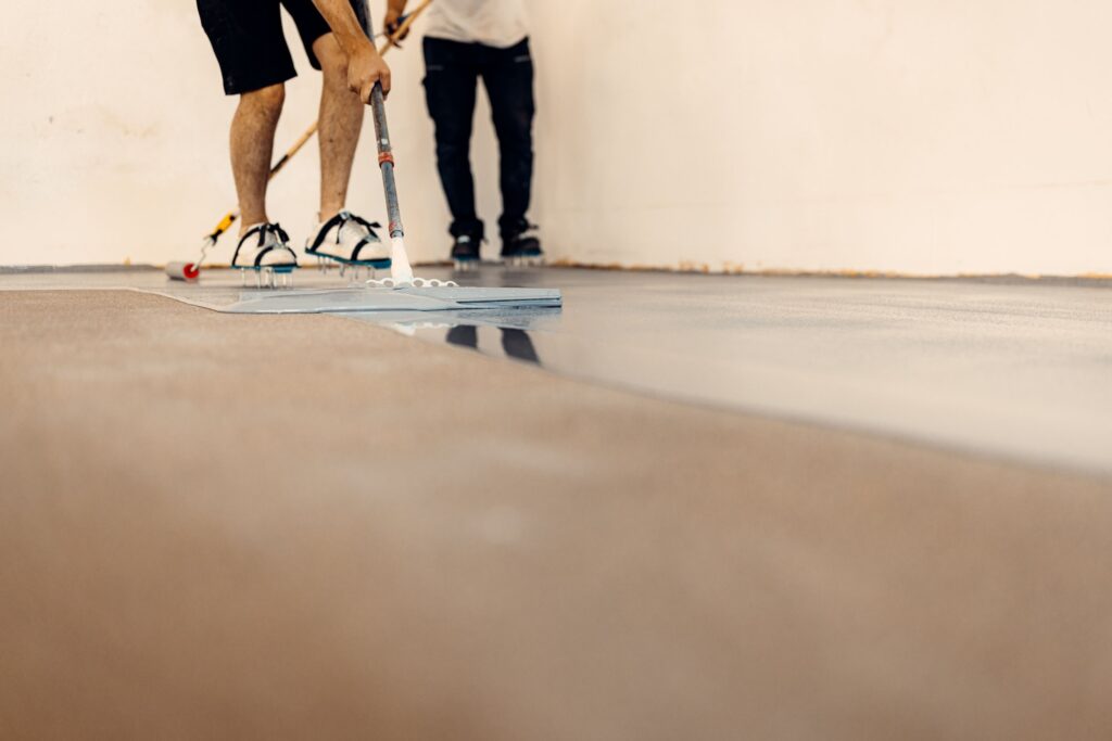 Closeup shot of worker applying floor primer with a special tool