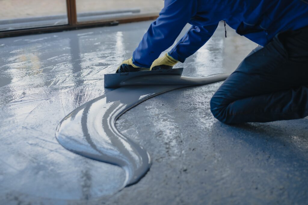 The worker applies gray epoxy resin to the new floor