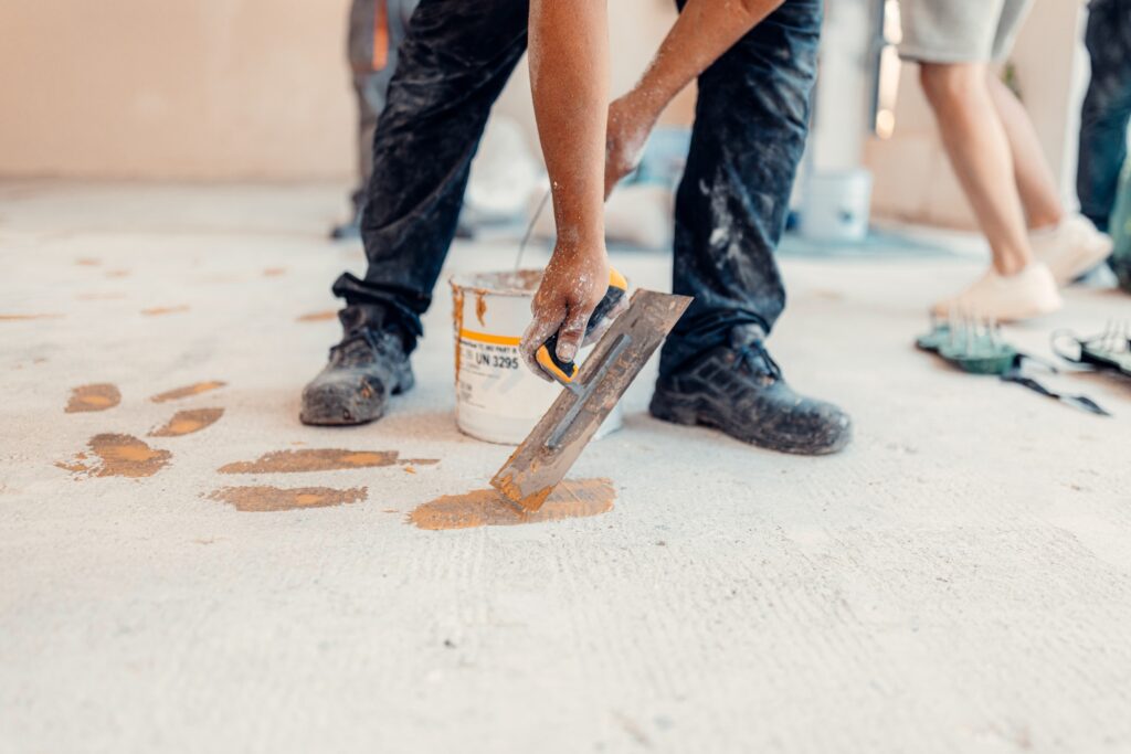 Worker applies floor primer with special tool