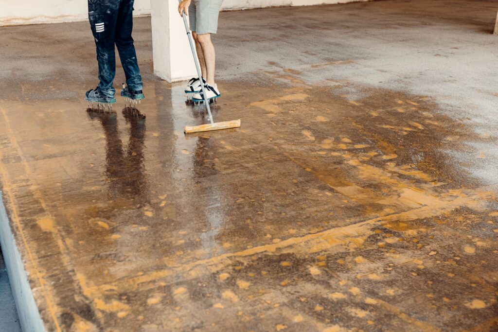 Worker applying floor primer with a special tool